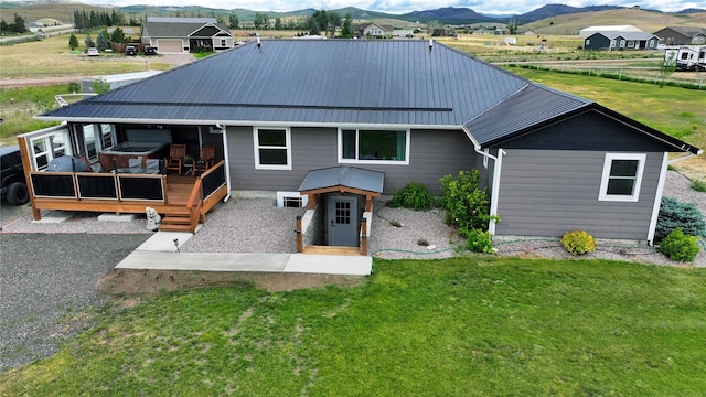 back of house featuring a deck with mountain view, a lawn, and metal roof