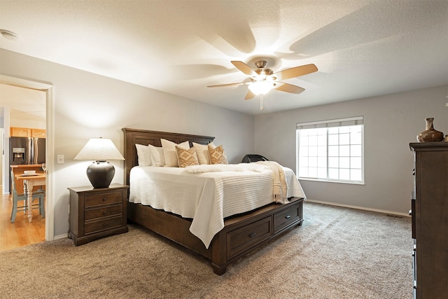 carpeted bedroom featuring a textured ceiling, a ceiling fan, stainless steel refrigerator with ice dispenser, and baseboards