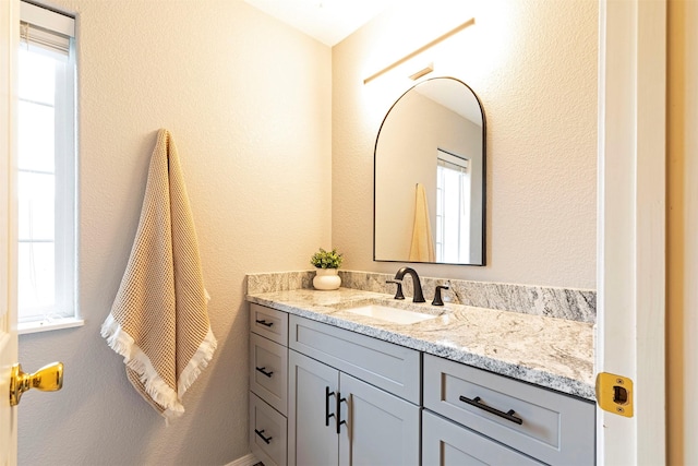 bathroom with a healthy amount of sunlight, vanity, and a textured wall