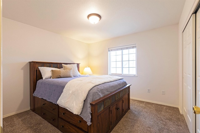 bedroom with dark colored carpet, a closet, and baseboards