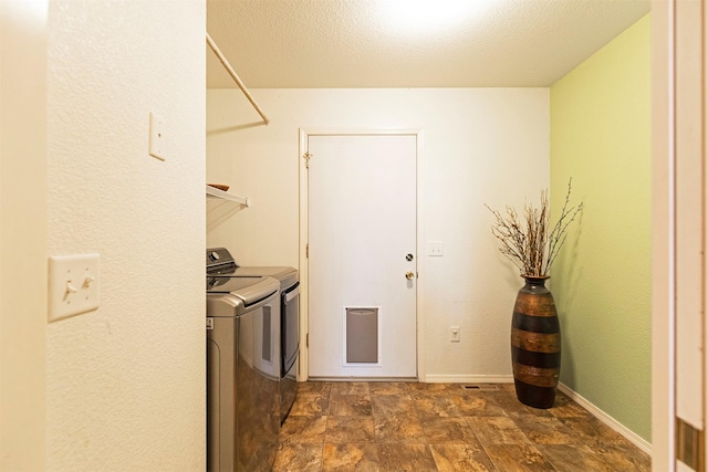 washroom with baseboards, laundry area, stone finish flooring, a textured ceiling, and washing machine and dryer