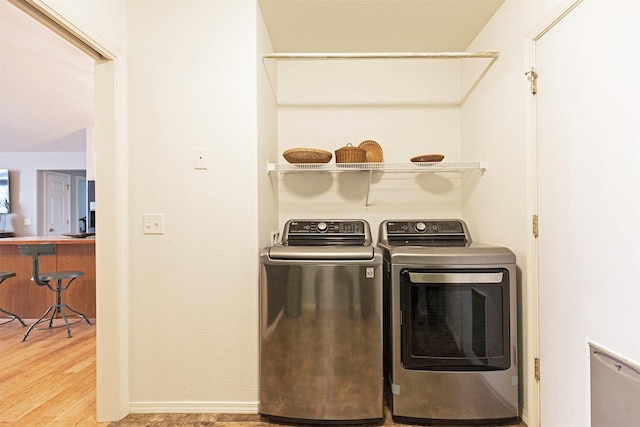 laundry room with laundry area, wood finished floors, baseboards, and separate washer and dryer