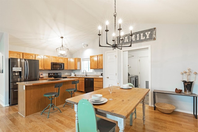 dining room featuring a notable chandelier, washing machine and dryer, light wood-type flooring, and vaulted ceiling