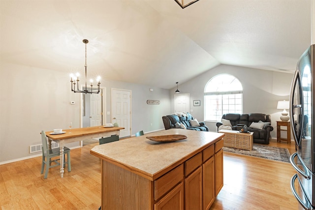 kitchen featuring lofted ceiling, light wood-style floors, a center island, and freestanding refrigerator