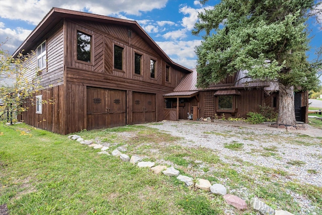 view of front facade with a front lawn, driveway, a barn, an attached garage, and metal roof