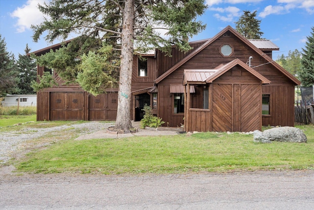 view of front of house featuring an outbuilding, a front lawn, a barn, and metal roof