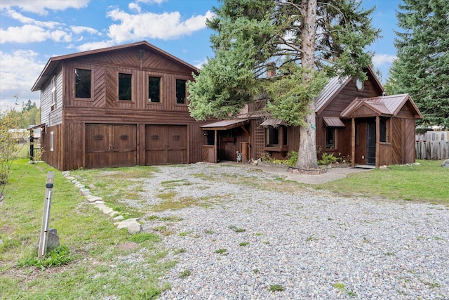 chalet / cabin featuring a front yard, an attached garage, fence, and driveway