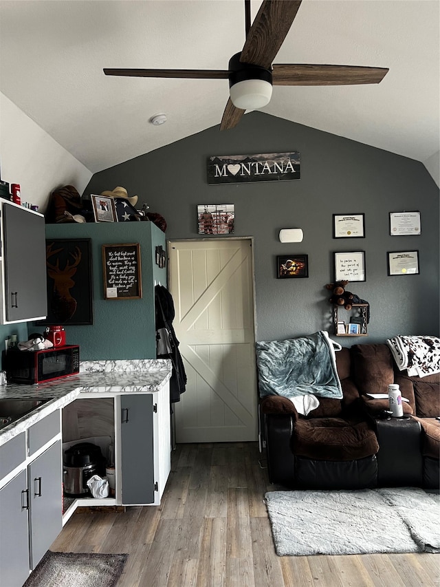 kitchen featuring wood finished floors, ceiling fan, light countertops, and vaulted ceiling