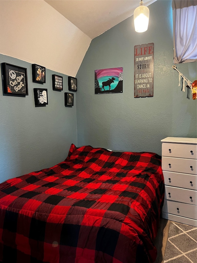 bedroom featuring lofted ceiling, carpet flooring, and a textured wall