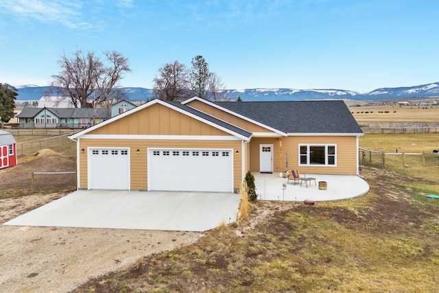 view of front facade with a mountain view, a garage, driveway, and fence