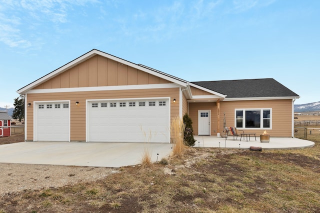 view of front of house featuring a garage, roof with shingles, and a patio area