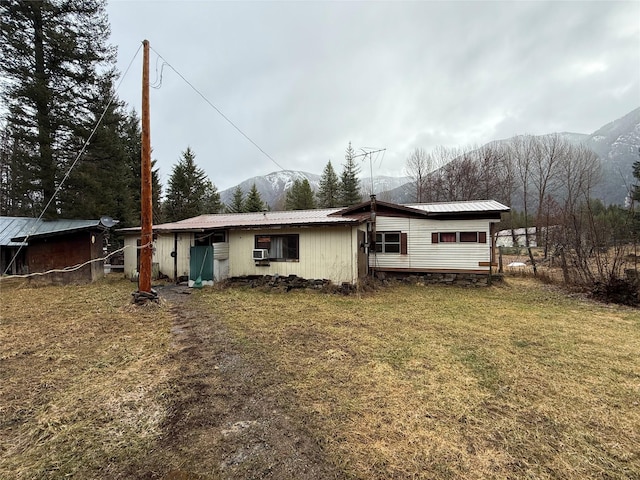 back of property with a mountain view, metal roof, and a yard