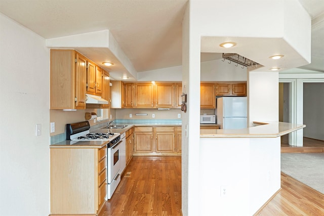 kitchen with under cabinet range hood, white appliances, lofted ceiling, and light wood-style flooring