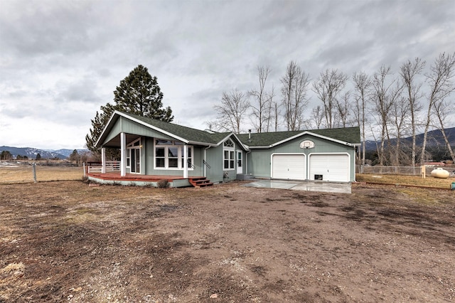 view of front of property featuring a mountain view, an attached garage, dirt driveway, and fence