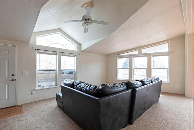 living area featuring ceiling fan, lofted ceiling, light colored carpet, and a textured ceiling