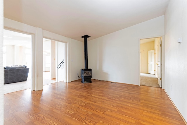 unfurnished living room featuring light wood-style flooring and a wood stove