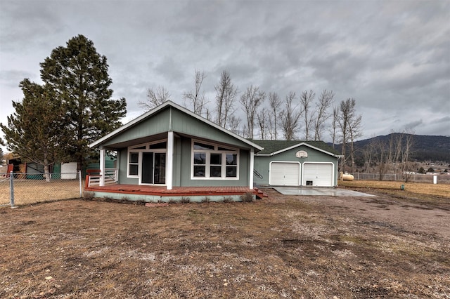 view of front of property with fence, driveway, a porch, an attached garage, and a mountain view