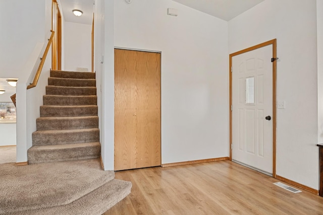 stairs featuring visible vents, wood finished floors, and baseboards