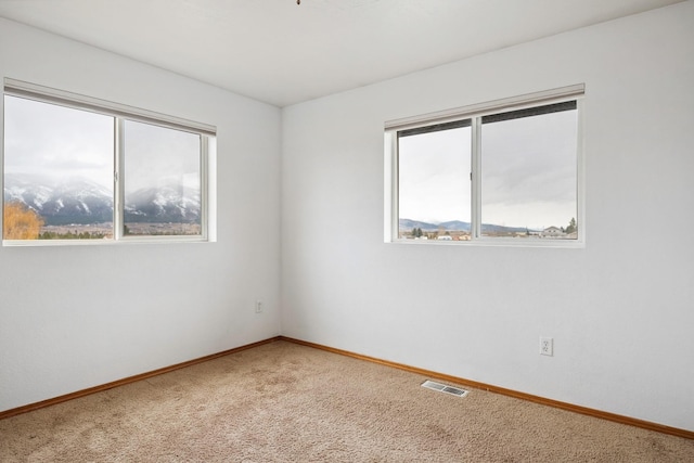 spare room with light carpet, visible vents, and baseboards