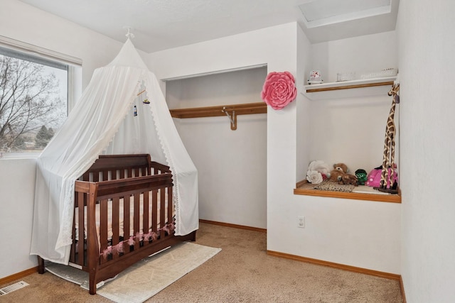 carpeted bedroom with a closet, visible vents, a nursery area, and baseboards