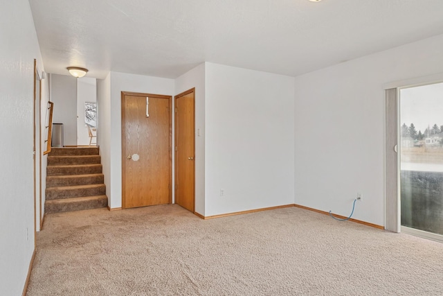 carpeted spare room with stairs and baseboards