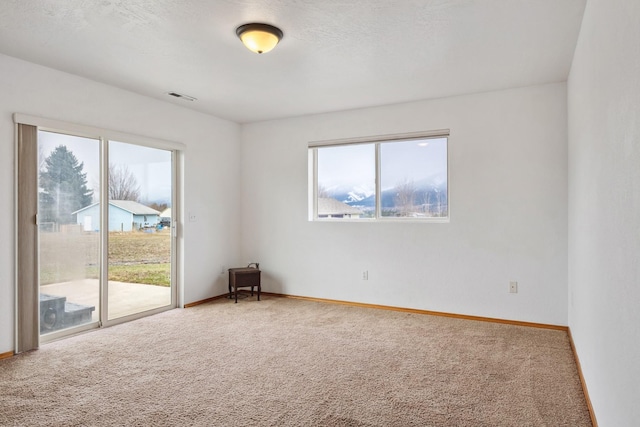 carpeted empty room featuring baseboards and visible vents