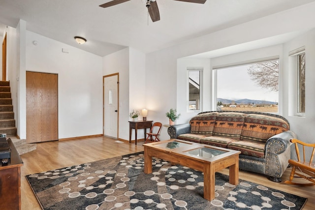 living area featuring baseboards, ceiling fan, stairs, vaulted ceiling, and wood finished floors