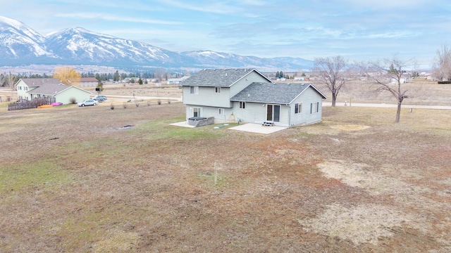 back of property featuring a mountain view, a patio area, and a shingled roof