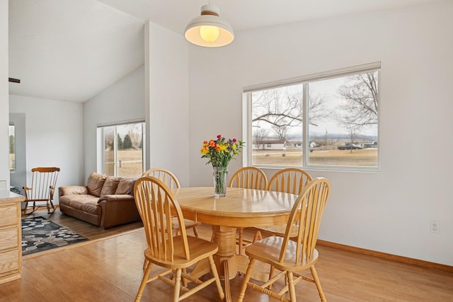 dining space with vaulted ceiling, light wood-style flooring, and baseboards