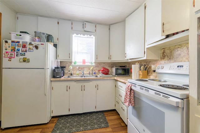 kitchen with white appliances, a sink, light countertops, light wood-style floors, and tasteful backsplash