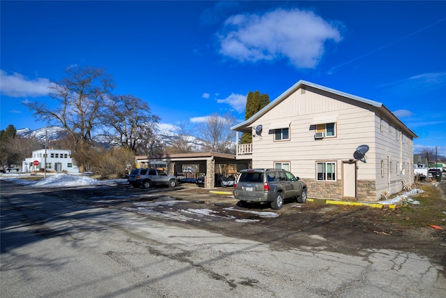 view of home's exterior with uncovered parking and stone siding