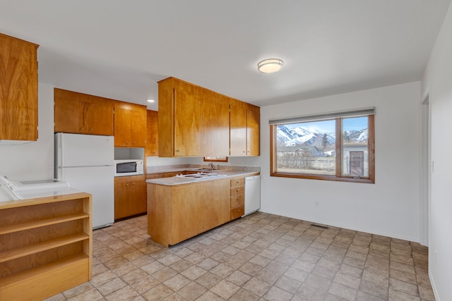 kitchen with visible vents, brown cabinets, white appliances, a peninsula, and light countertops