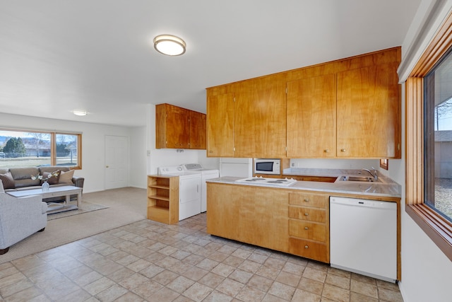 kitchen with white appliances, a sink, light countertops, washing machine and dryer, and open floor plan