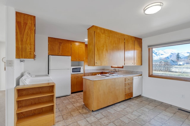 kitchen featuring visible vents, light countertops, a peninsula, independent washer and dryer, and white appliances