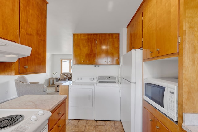 kitchen with washing machine and clothes dryer, brown cabinets, white appliances, and light countertops