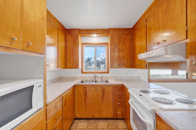 kitchen with white appliances, light countertops, under cabinet range hood, and a sink