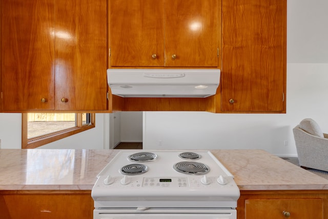 kitchen with under cabinet range hood, brown cabinetry, light countertops, and white range with electric stovetop