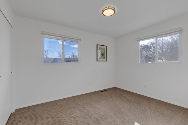 unfurnished room with a healthy amount of sunlight, baseboards, and carpet floors