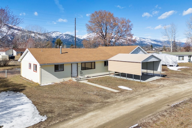 single story home featuring a mountain view, fence, roof with shingles, and dirt driveway