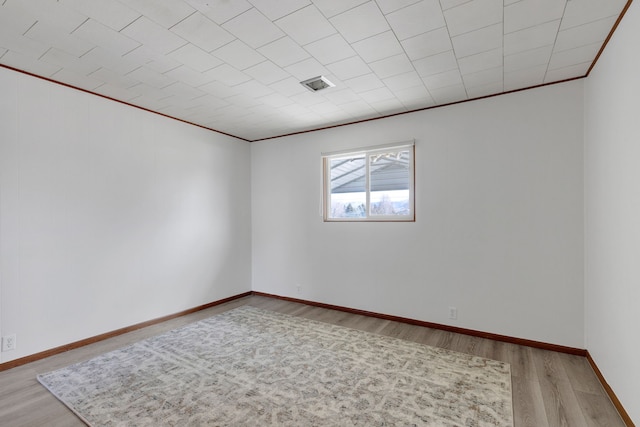 unfurnished room featuring visible vents, ornamental molding, baseboards, and wood finished floors