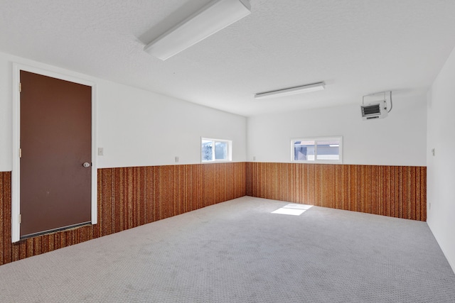 carpeted spare room featuring wainscoting, a textured ceiling, and wood walls