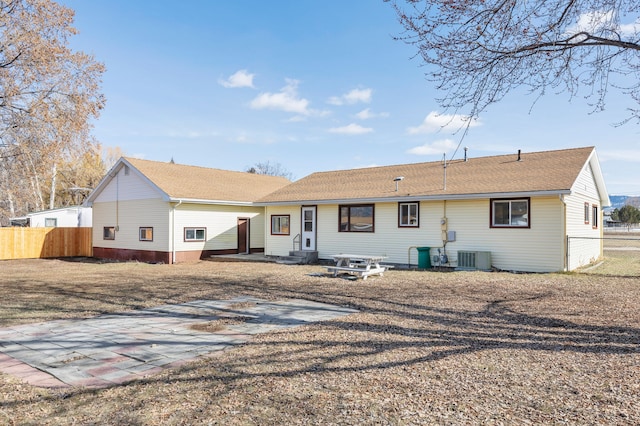 rear view of property with cooling unit, entry steps, roof with shingles, and fence