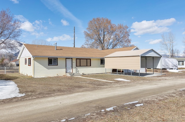 ranch-style house with driveway, entry steps, fence, roof with shingles, and a detached carport