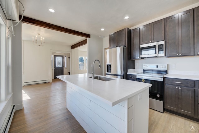 kitchen featuring baseboard heating, dark brown cabinets, appliances with stainless steel finishes, and a sink