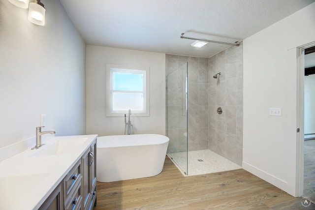 full bathroom with a soaking tub, tiled shower, wood finished floors, and a sink