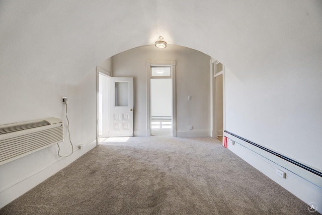 carpeted spare room with arched walkways and a baseboard radiator