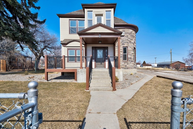 view of front of house with stone siding, a shingled roof, and a front yard