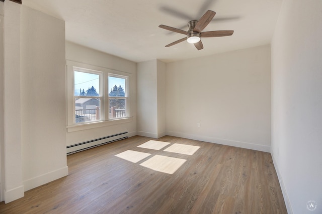 empty room featuring ceiling fan, a baseboard heating unit, baseboards, and wood finished floors