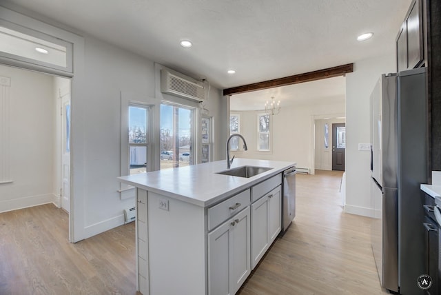 kitchen with light wood finished floors, a baseboard radiator, a sink, stainless steel appliances, and light countertops