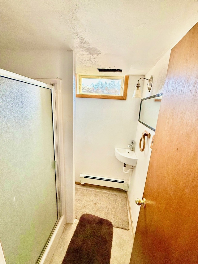 full bathroom featuring a sink, a baseboard radiator, and a stall shower